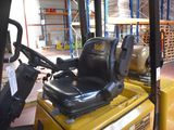 a yellow forklift with a black seat in a warehouse