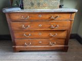 une commode en bois avec un plateau en marbre, posée sur un parquet