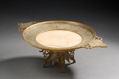 une assiette en or posée sur un socle, sur une surface grise
