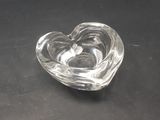 a glass heart shaped ashtray on a black table