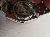 someone is holding a watch in their hand on a white surface