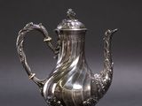une théière ancienne en argent, ornée d'une anse en forme de dragon, sur fond gris