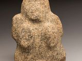 un gros plan sur une statue en pierre représentant une personne, posée sur une surface grise