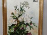 une peinture à l'huile représentant des fleurs, dans un cadre doré, accrochée à un mur blanc