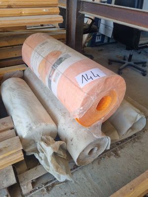 several rolls of wood sit on top of pallets in a warehouse