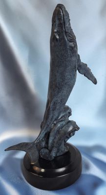 statue représentant un dauphin bondissant hors de l'eau, posée sur un socle noir