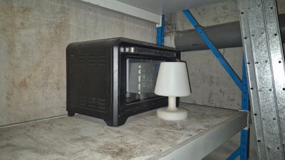 un micro-ondes posé sur une étagère, avec une lampe posée dessus