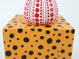a red and black polka dot vase sitting on top of a yellow box
