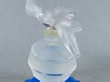 a clear glass bottle with a blue base and a bird on top
