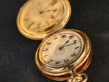 une montre de poche en or posée sur un tissu noir