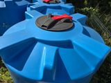 many blue water tanks with red handles in the grass
