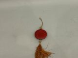 Gros plan sur une perle rouge ornée d'un pompon, posée sur une surface blanche