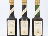 trois bouteilles de vin sont alignées sur une surface blanche