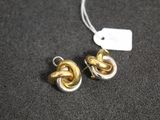une paire de boucles d'oreilles en or et en argent posées sur une surface noire