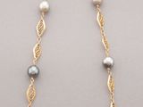 a close up of a necklace with pearls and gold chains