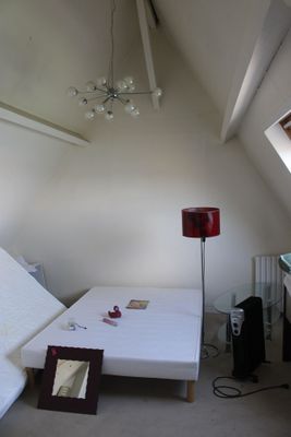 un lit dans un coin d'une pièce où se trouve une lampe rouge