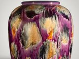 a purple vase that has a lot of paint on it