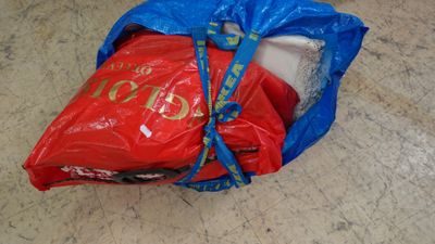 un sac rouge muni d'une poignée bleue posé par terre