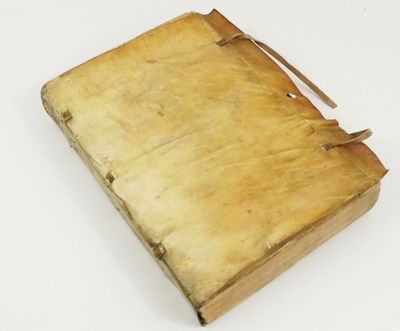 un vieux livre repose sur une surface blanche, retenu par une lanière marron