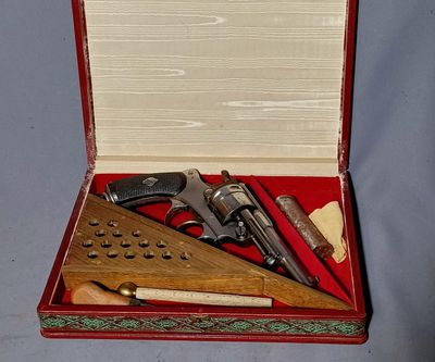 a red case with a gun, a ruler, and other items in it