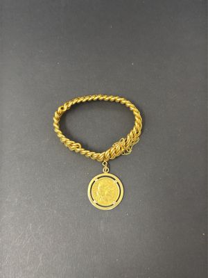 a gold chain bracelet with a coin charm on it