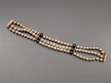 a close up of a bracelet with pearls on a gray surface