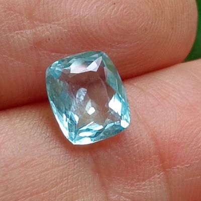 une personne tenant une topaze bleue dans la main