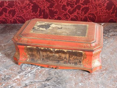une boîte rouge posée sur un sol en marbre, avec un mur rouge en arrière-plan
