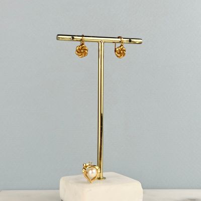 un présentoir à boucles d'oreilles en or posé sur un bloc de marbre