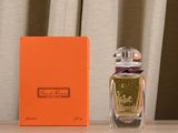 une boîte orange posée à côté d'un flacon de parfum sur une table