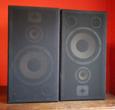 two speakers are sitting on a shelf in front of a red wall