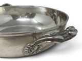 a silver bowl with a spoon in it on a white surface
