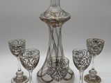 four wine glasses and a decanter on the table