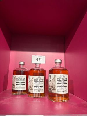 trois bouteilles de whisky sont posées sur une étagère, dans une boîte rose