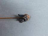 a silver and gold pin with a bird on it