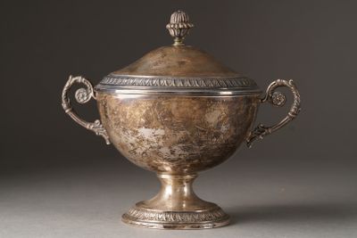 une coupe ancienne en argent, munie d'un couvercle et d'anses, posée sur un support gris