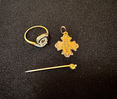 deux bagues en or et une croix en or posées sur un tissu noir