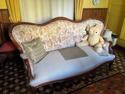 un ours en peluche assis sur un canapé dans un salon