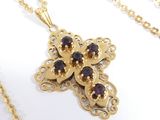 an image of a gold cross with garnets on a chain