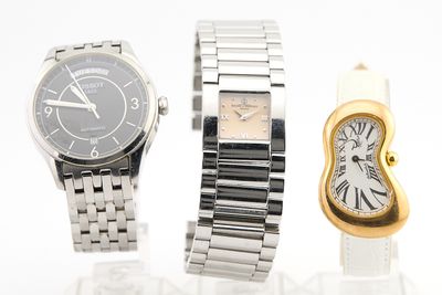 Deux montres et une montre en or sont posées sur une surface blanche