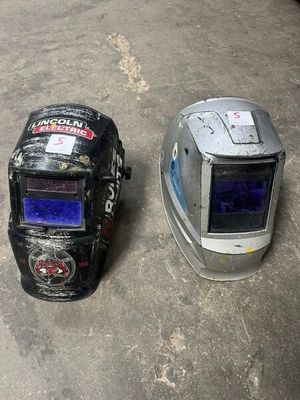 two welding helmets sitting on the ground next to each other