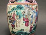 a vase with a painting on it sitting on a table