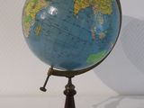 un petit globe bleu et jaune posé sur un socle en bois