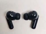 two black earphones sitting on top of each other on a white surface