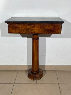 a small wooden table with a black top on a tiled floor