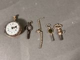 une montre de poche, une clé et un porte-clés posés sur une table