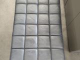 grey leather bench with a metal frame in the middle of a room