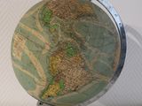 a small globe on a stand on a white surface