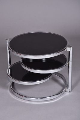 un gros plan d'une table basse à trois niveaux avec un plateau en verre noir