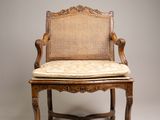 une image représentant une chaise sur laquelle est posé un coussin, avec une pièce de monnaie en arrière-plan